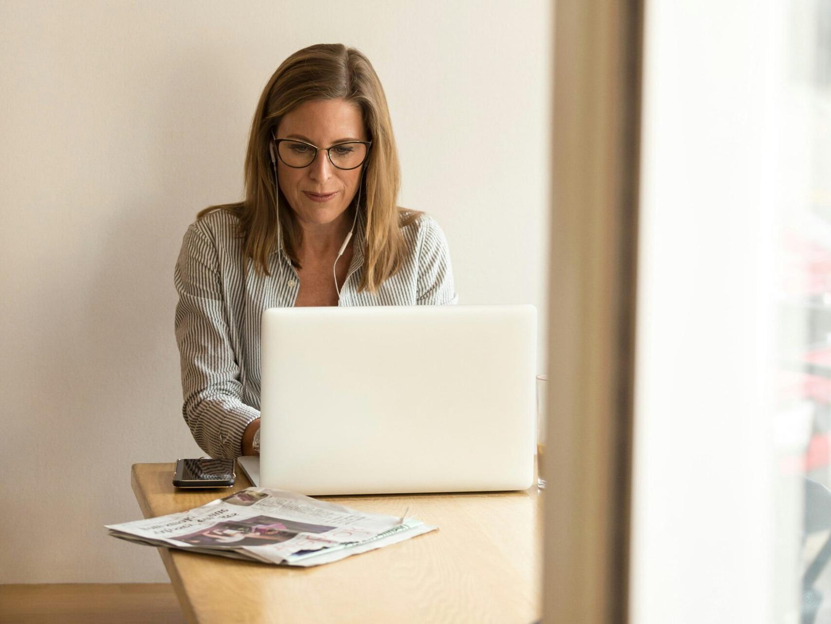 Woman with glasses sitting at a table using a laptop